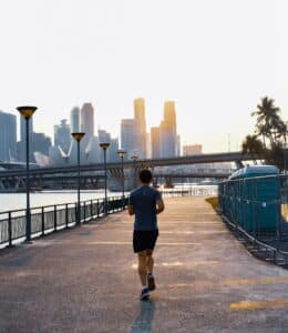 Man running by a sidewalk with buildings in the background