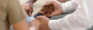 A group of people holding hands during group therapy