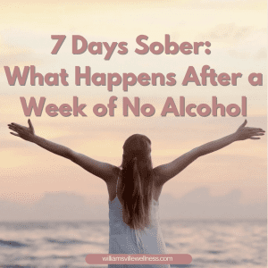 Woman holding her hands up in the air in a victory pose with an ocean horizon in front of her celebrating 7 days sober